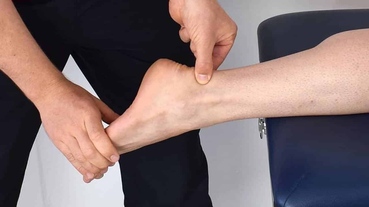 Physiotherapist performing clinical assessment of a patient's Achilles tendon and heel